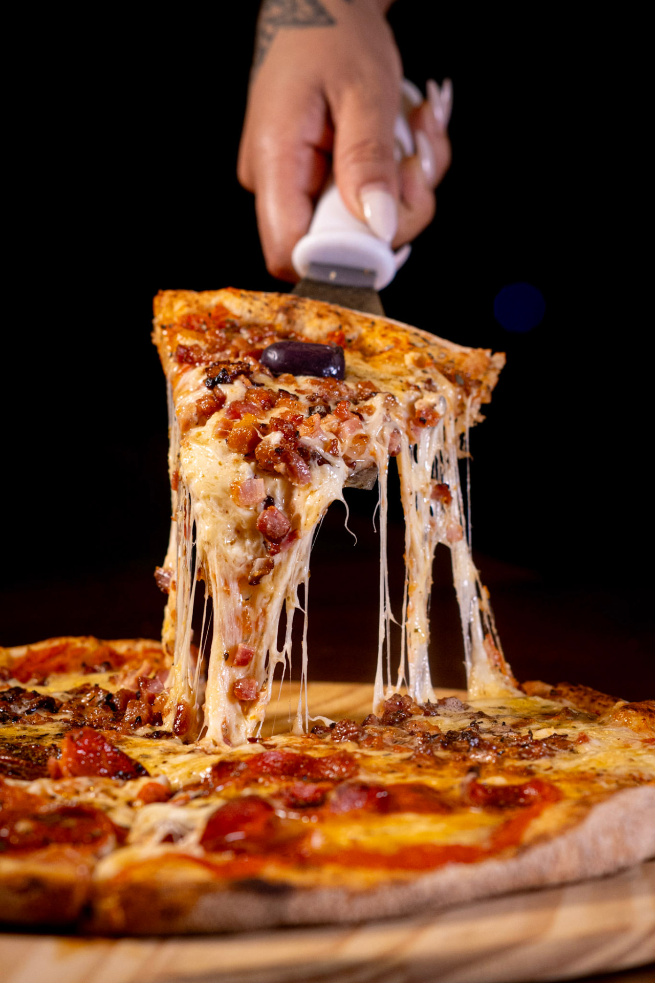 Fatia de pizza Capellini sendo servida com queijo derretido